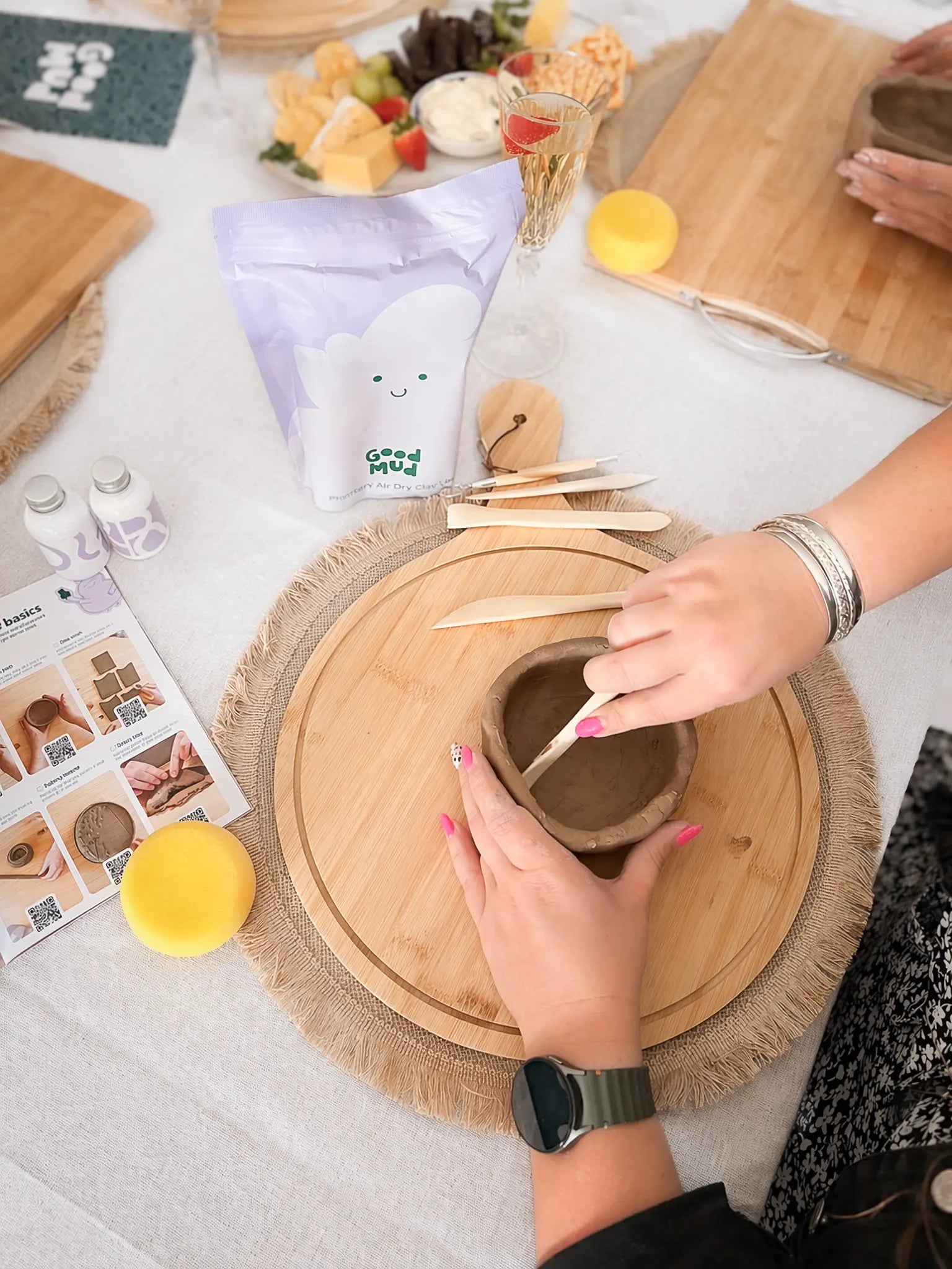 Person shaping clay at a table using a DIY pottery kit at home