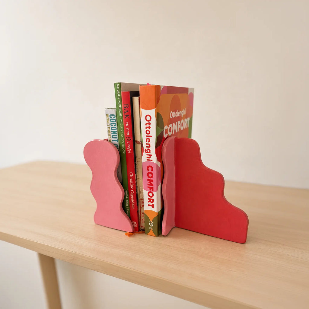 Handmade clay bookends holding books on shelf