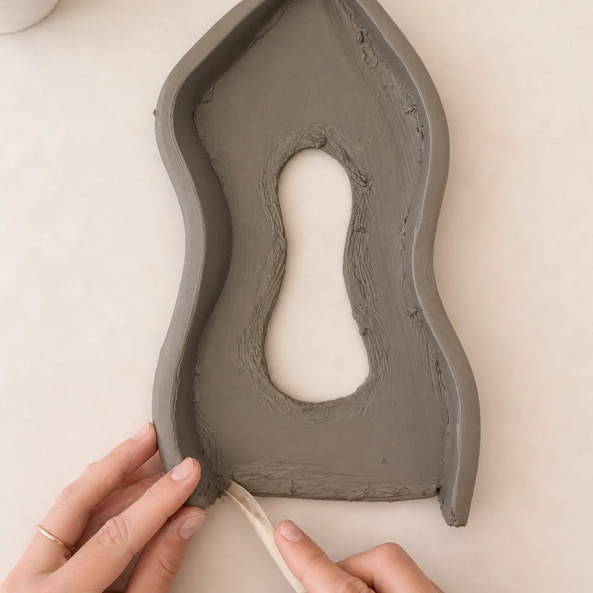Hands shaping air dry clay into a pottery piece at home