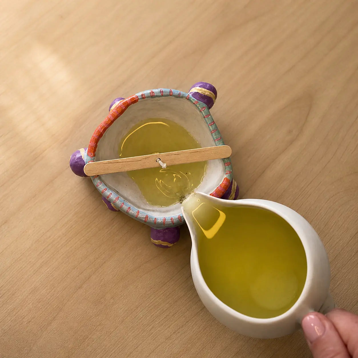 Pouring wax into a handmade clay candle holder